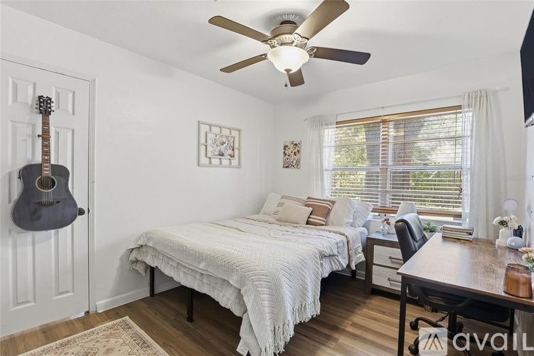 A bedroom with a bed, a desk, and a guitar hanging on the wall.