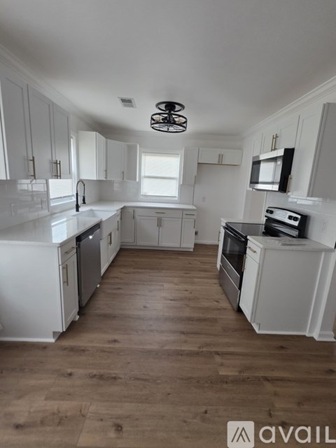 A kitchen with white cabinets and a wooden floor.