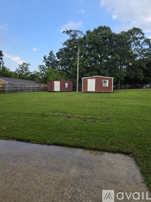 A grassy field with two buildings and a puddle of water.