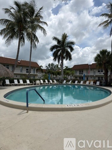 A pool surrounded by palm trees and lounge chairs.