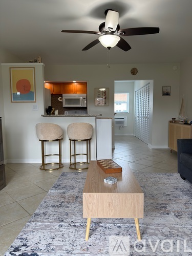 A living room with a ceiling fan and a rug on the floor.