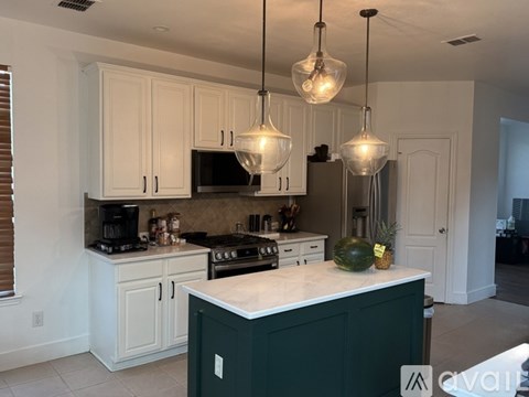 A kitchen with white cabinets and a green island.
