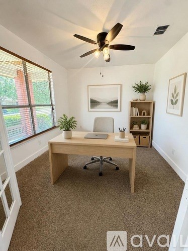 A room with a desk, chair, and a ceiling fan.