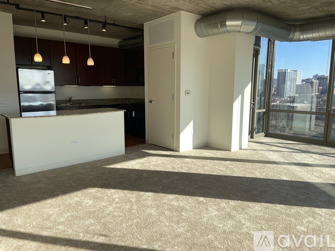 A well-lit, empty office space with a kitchenette and a view of the city.