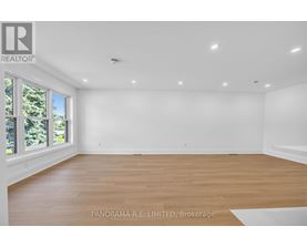 A spacious room with wooden flooring and white walls.