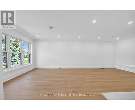 A spacious room with wooden flooring and white walls.