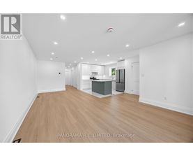 A spacious living room with wood flooring and white walls.