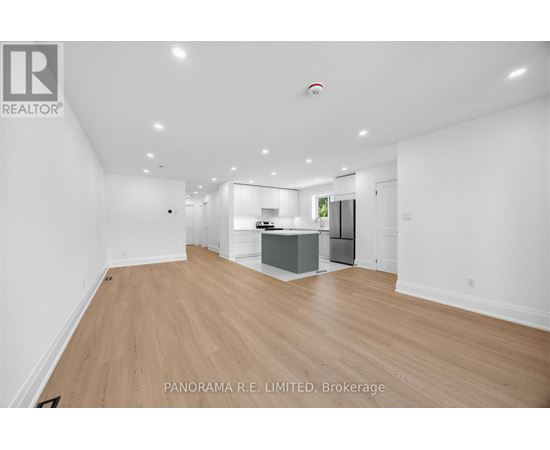 A spacious living room with wood flooring and white walls.