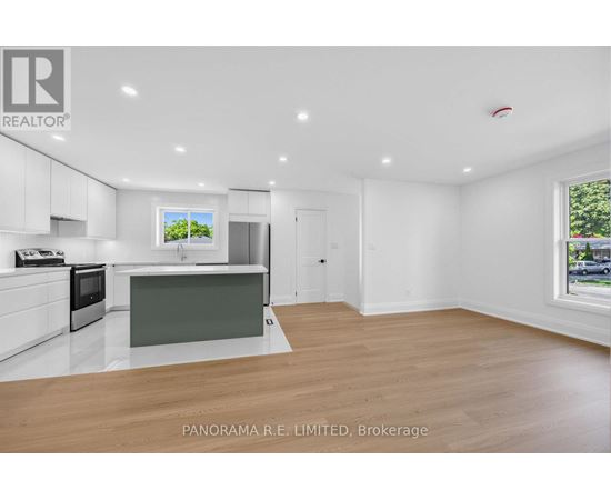 A spacious kitchen with white cabinets and a wooden floor.