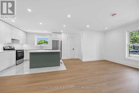 A spacious kitchen with white cabinets and a wooden floor.