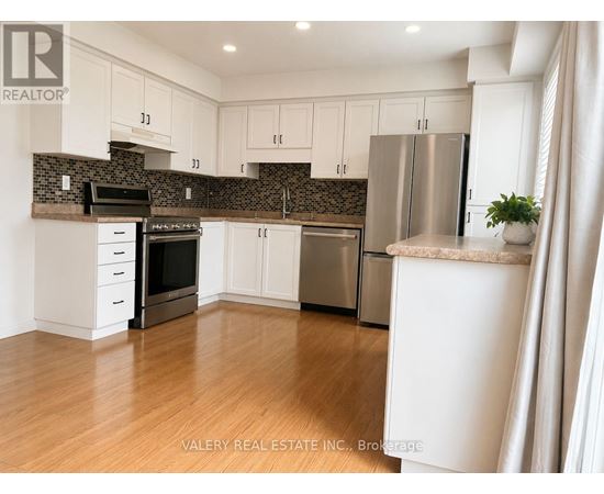 A kitchen with white cabinets and a stainless steel refrigerator.