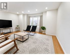 A living room with a flat screen TV, two chairs, a coffee table, and a rug.