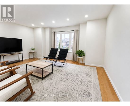 A living room with a flat screen TV, two chairs, a coffee table, and a rug.
