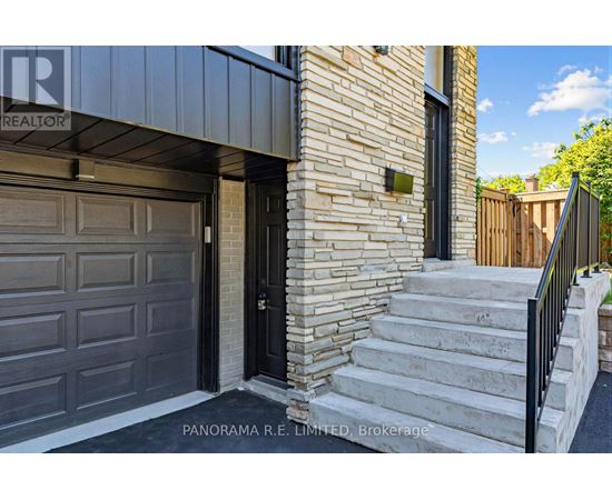 A house with a black garage door and a brick wall.