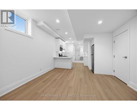 A spacious room with wooden flooring and white walls.