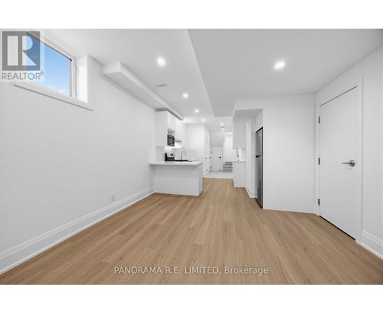 A spacious room with wooden flooring and white walls.