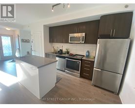 A kitchen with a refrigerator, microwave, and oven.