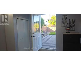A white door with a glass window is open to a backyard.
