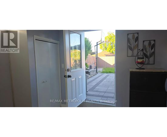 A white door with a glass window is open to a backyard.