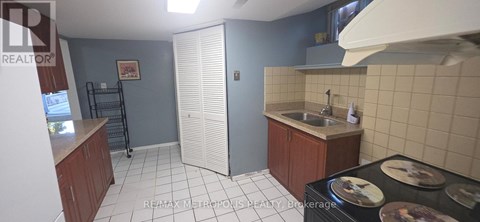 A kitchen with a sink, stove, and cabinets.