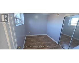 A room with a wooden floor and a glass door leading to another room.