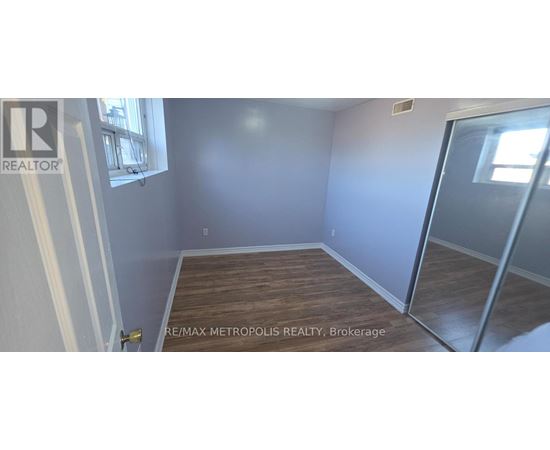 A room with a wooden floor and a glass door leading to another room.