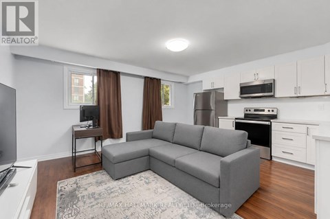 A grey sofa in a living room with a television and a kitchen area in the background.