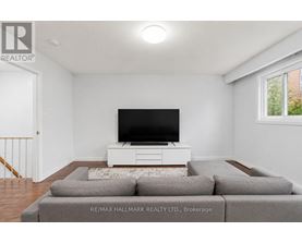 A living room with a grey couch and a white television stand.