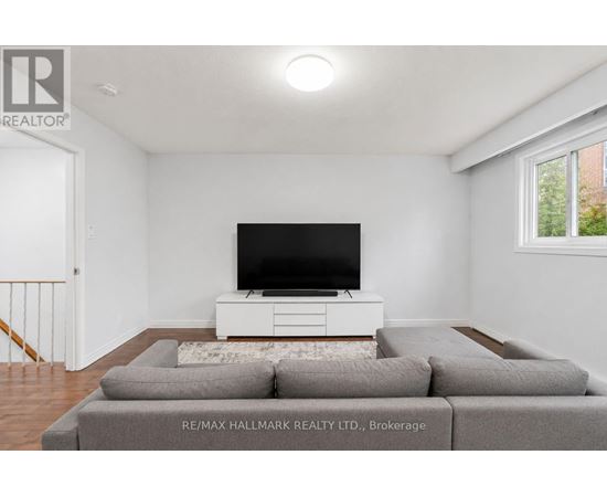 A living room with a grey couch and a white television stand.