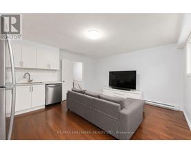A living room with a grey couch and a television on a white stand.