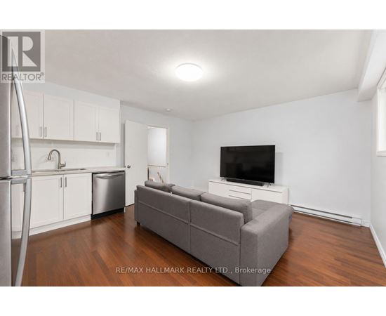 A living room with a grey couch and a television on a white stand.