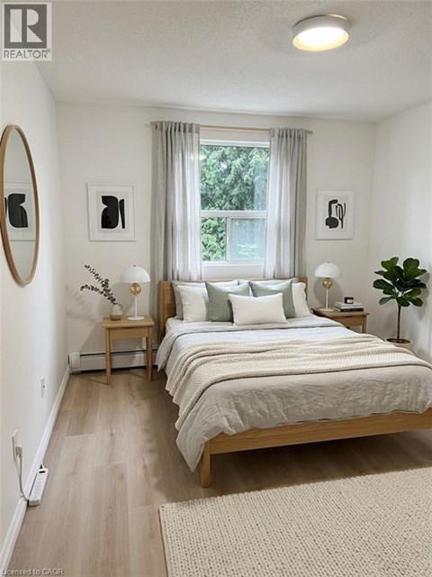 A bedroom with a large bed and a window with curtains.