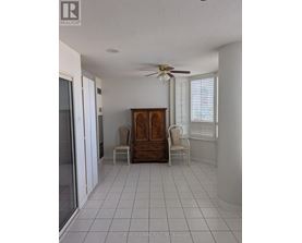A room with a ceiling fan and two chairs.