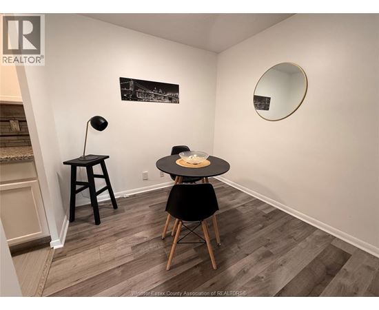 A room with a table and chairs and a framed picture on the wall.