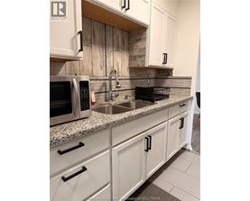 A kitchen with a sink, microwave, and cabinets.