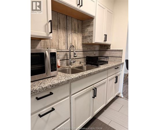 A kitchen with a sink, microwave, and cabinets.