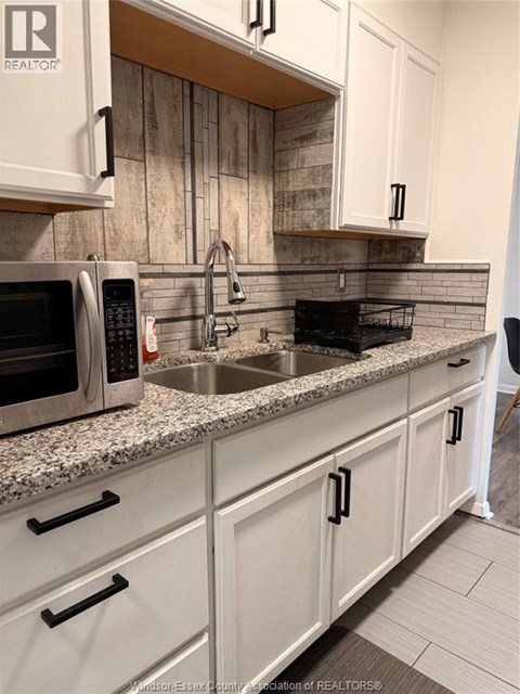 A kitchen with a sink, microwave, and cabinets.