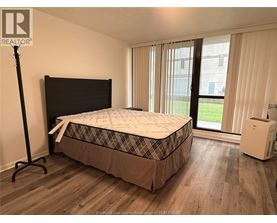 A bedroom with a bed, a window with curtains, and a white air conditioning unit.