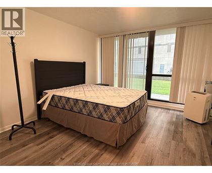 A bedroom with a bed, a window with curtains, and a white air conditioning unit.