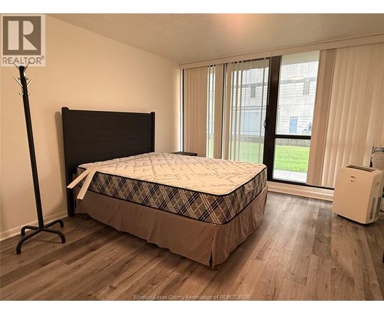 A bedroom with a bed, a window with curtains, and a white air conditioning unit.