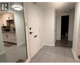 A hallway with a door on the right and a kitchen in the background.