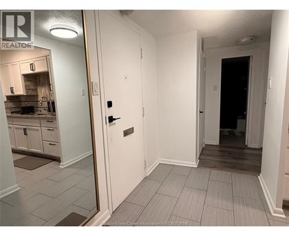 A hallway with a door on the right and a kitchen in the background.