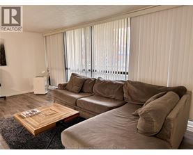 A living room with a couch, coffee table, and window with blinds.