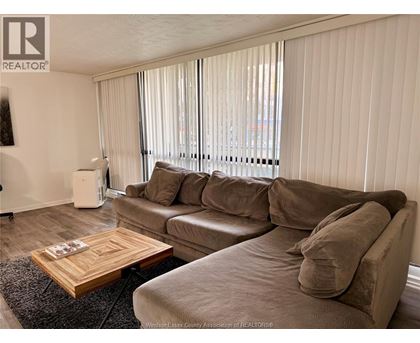 A living room with a couch, coffee table, and window with blinds.