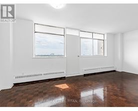 A large, empty room with a view of the city through the windows.
