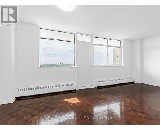 A large, empty room with a view of the city through the windows.