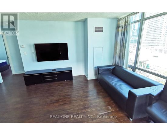 A living room with a black leather couch and a flat screen TV.