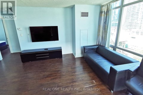 A living room with a black leather couch and a flat screen TV.