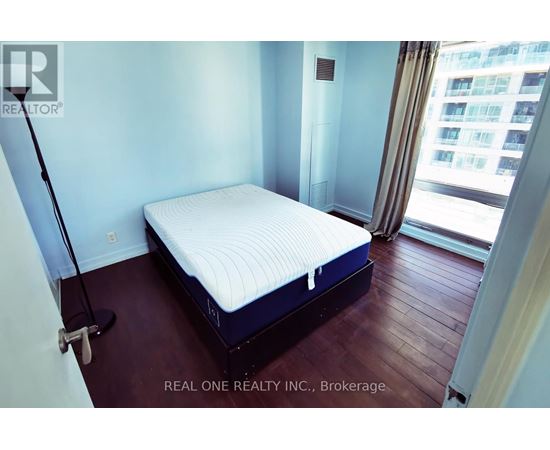 A bedroom with a neatly made bed and a window overlooking a cityscape.