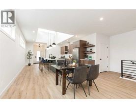 A modern dining room with a wooden floor and a long table with chairs.